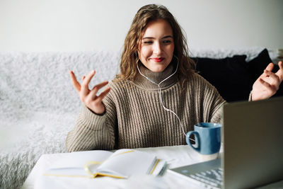 Portrait of young woman using mobile phone while sitting on table