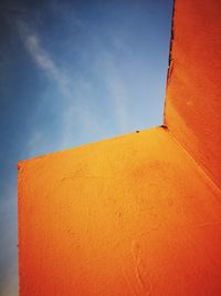 Low angle view of orange wall against sky