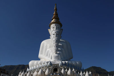 Low angle view of traditional buddha against blue sky