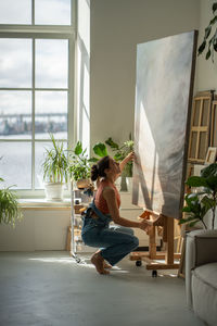 Side view of young woman sitting on sofa at home