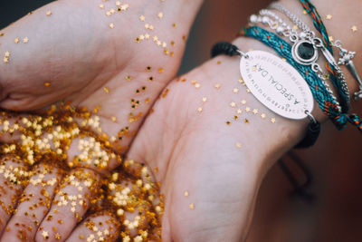 Cropped hands of woman holding golden star shape glitters