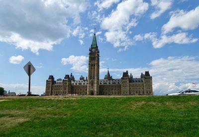 Historic building on field against cloudy sky