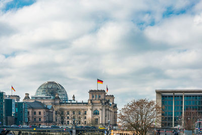 Buildings in city against cloudy sky