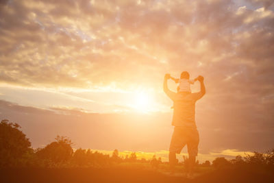 Silhouette man photographing on field against sky during sunset