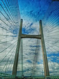 Low angle view of suspension bridge against cloudy sky