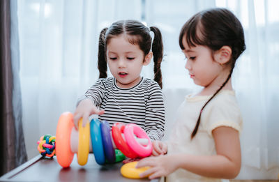 Sisters playing with multi colored toys at home