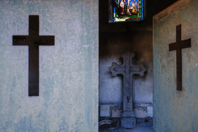 View of cross in cemetery against building