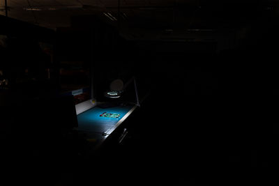 Low angle view of illuminated laptop on table in darkroom