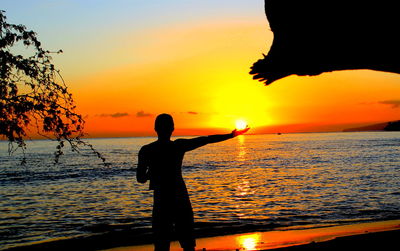 Silhouette man standing at beach during sunset