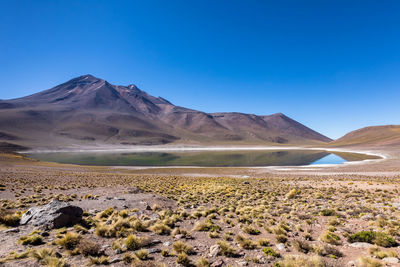 Scenic view of arid landscape against clear blue sky