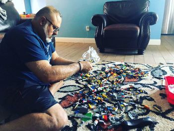 Side view of man sitting on chair at home