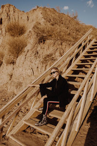 Man sitting on wood against sky