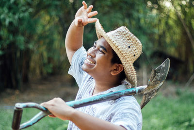 Smiling man holding shovel standing outdoors