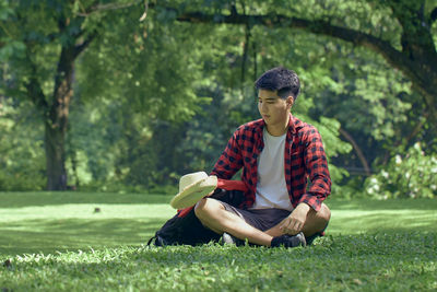 Full length of young man sitting on land