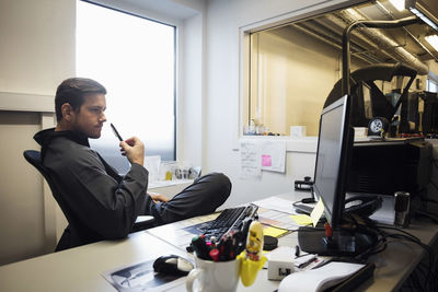 Confident male owner looking at computer monitor in office