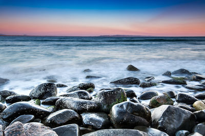 Scenic view of sea and rocks during sunset