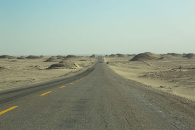 Road amidst desert against clear sky