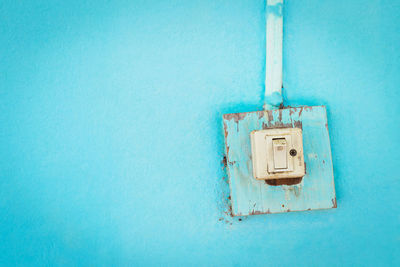 Close-up of electric light on blue wall