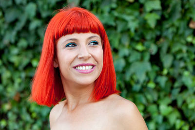 Close-up of smiling woman standing against plants