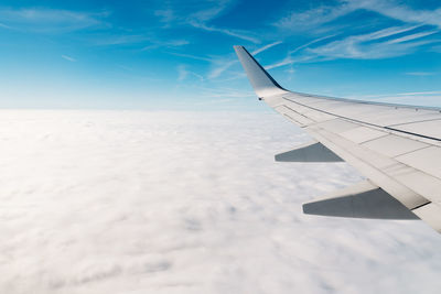 Cropped image of airplane wing flying against sky