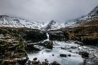 Scenic view of waterfall against mountains during winter