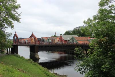 Arch bridge over river against cloudy sky