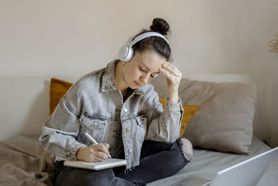 Young beautiful woman with casual clothes sitting on the bed at home with laptop computer 