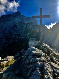 Cross on rock against sky