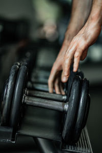 Midsection of man lifting dumbbell in gym