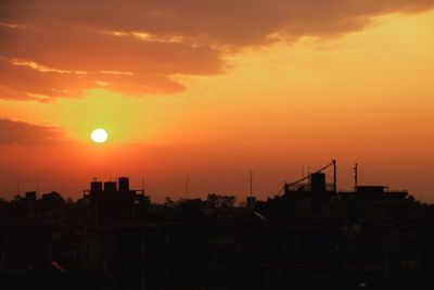 Silhouette cranes against orange sky