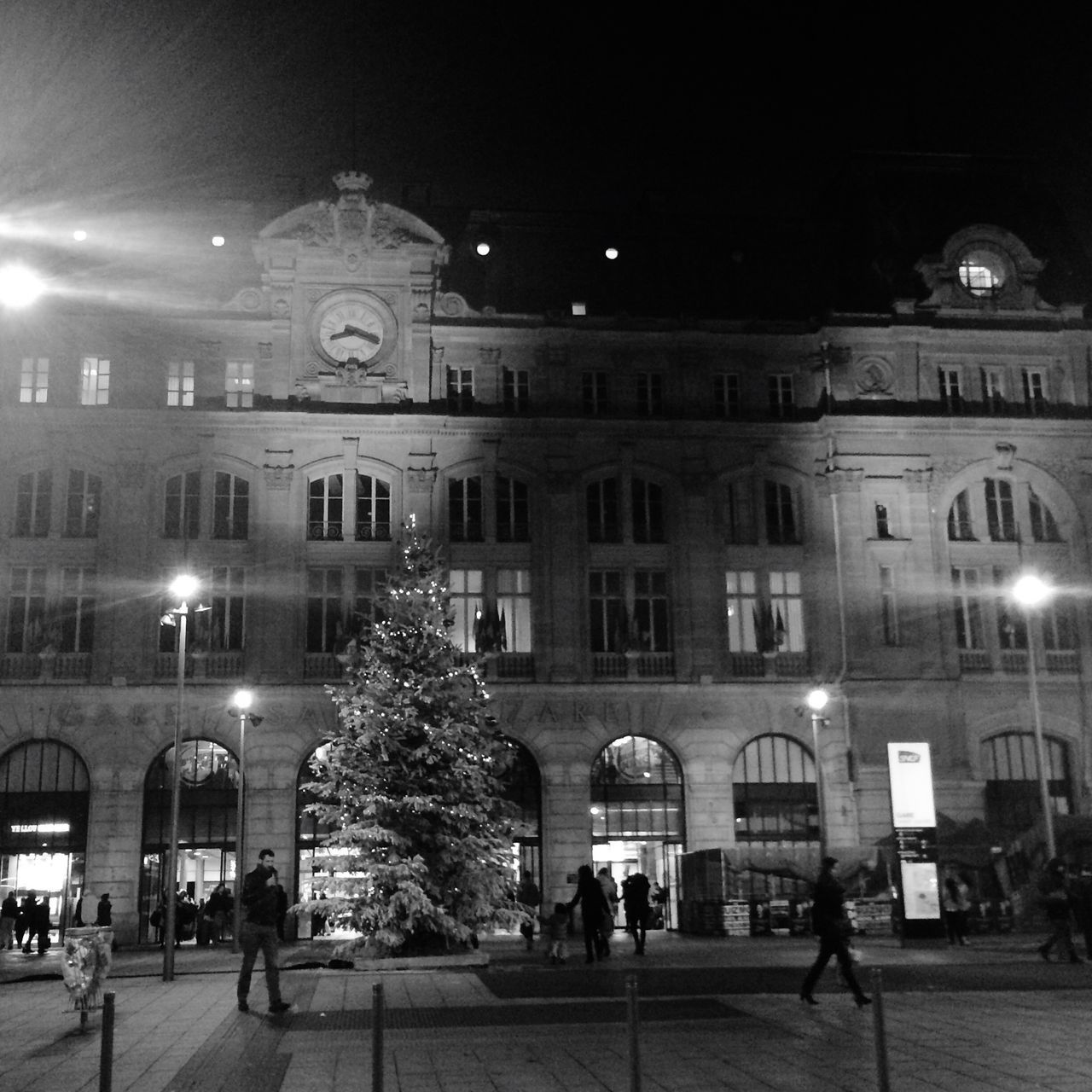 night, illuminated, building exterior, architecture, built structure, city, street light, street, incidental people, lighting equipment, facade, city life, arch, building, outdoors, sky, walking, person, large group of people