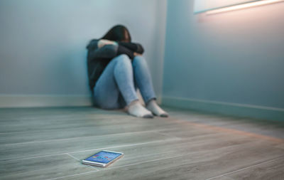 Rear view of woman sitting on hardwood floor