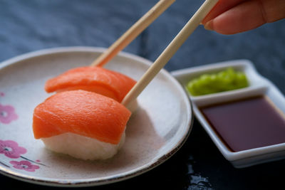 Cropped hand of woman having sushi in plate on slate