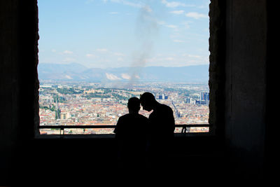 Rear view of silhouette man and woman looking through window