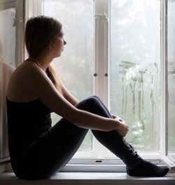 Woman looking through window during monsoon