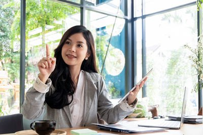 Thoughtful businesswoman pointing in office at desk