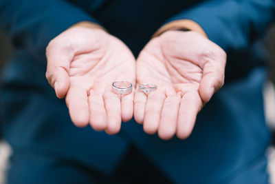 Close-up of man holding wedding rings