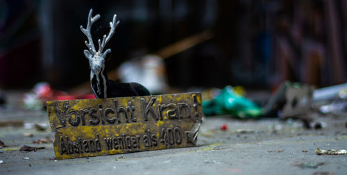 Close-up of abandoned deer figurine with text on street