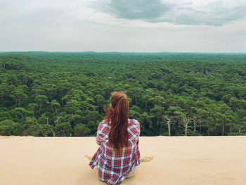 Rear view of woman walking on beach against sky