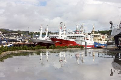 Boats moored at harbor against sky