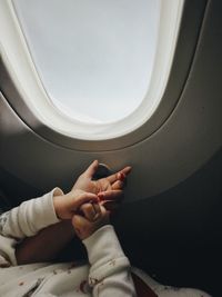 Low section of woman and baby sitting on airplane window