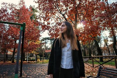 Young woman looking away while standing on field