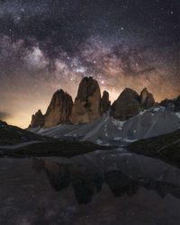 Reflection of mountains in lake against star field