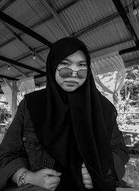 Portrait of young woman standing against building