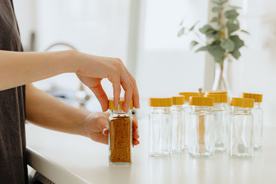 A girl pours spice seasoning from a bag into a jar.