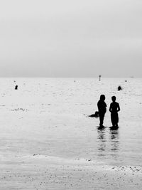 Silhouette men on beach against sky