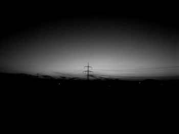 Silhouette electricity pylon against clear sky