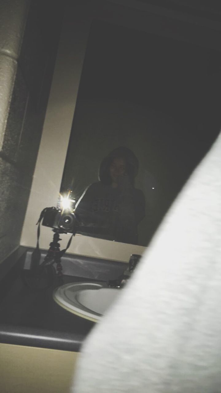 REFLECTION OF YOUNG WOMAN ON MIRROR IN ILLUMINATED ROOM