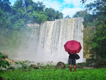 Full length of man standing against waterfall