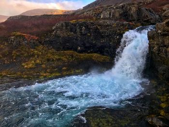 Scenic view of waterfall against sky